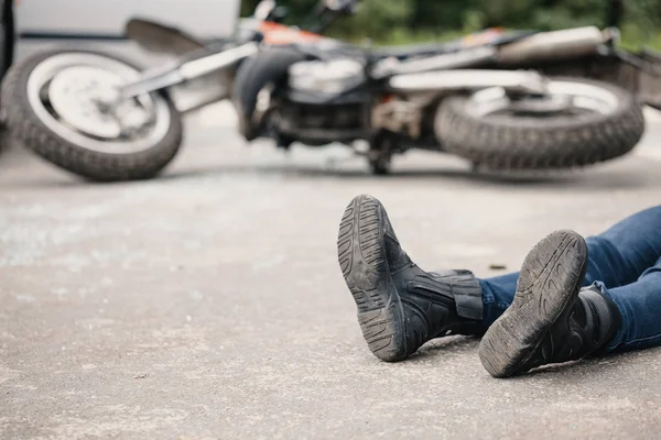 衝突後道路とバック グラウンドでバイクの上に横たわる無責任なモーターサイク リスト — ストック写真