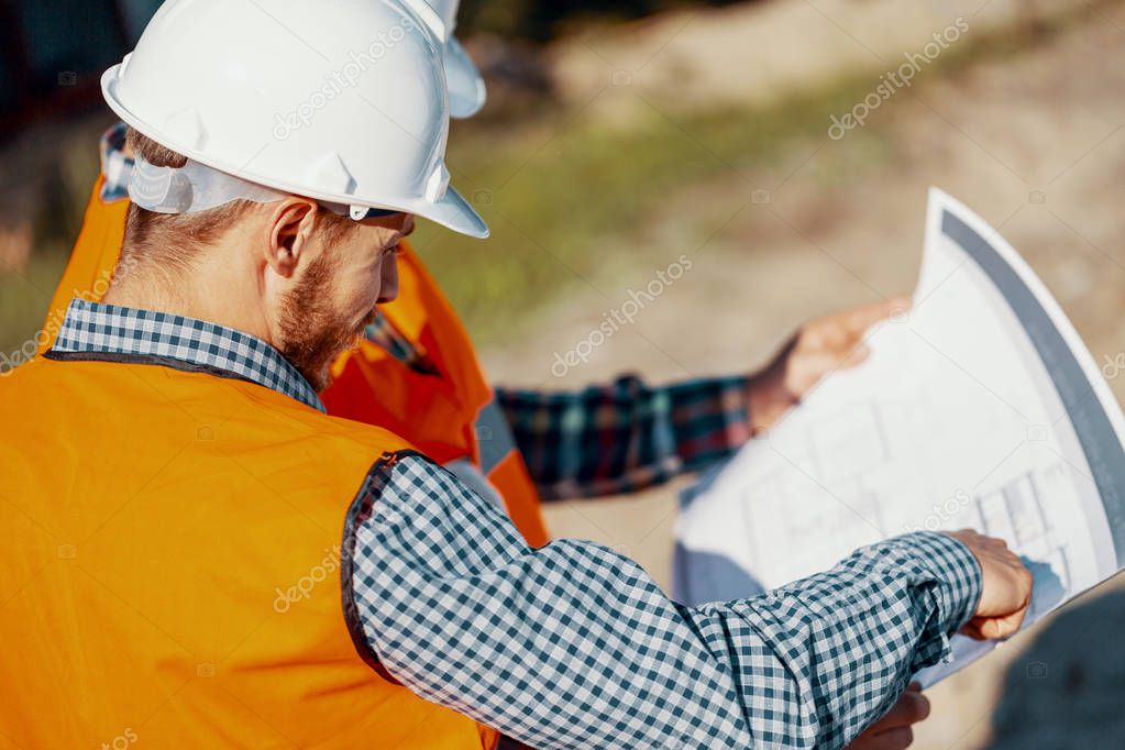 Engineer in white helmet consulting on the project plan with construction manager