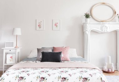 Parlak kadınsı İngiliz tarzı yatak odası iç çift kişilik yatak, basit gül posterler, mockup çerçeve ve sahte şömine mum ile gerçek fotoğraf