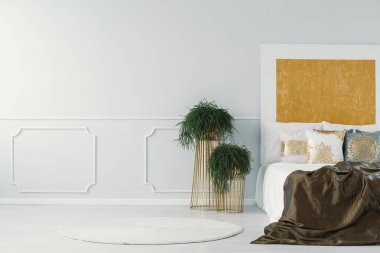 Bitkiler ve çift kişilik yatak bir otel odası iç yanındaki boş bir duvara duvar kalıp. Gerçek bir fotoğraf. Logonuzu buraya koyun