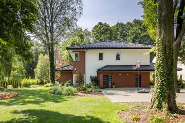 Modern ev, çalılar ve ağaçlar ve basketbol Bahçesi ile bahçe. Gerçek fotoğraf