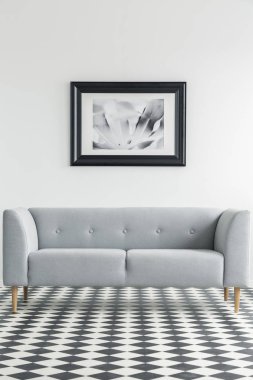 Basit, gri kanepe oturma odası iç arka planda bir posteri ile damalı bir katta. Gerçek fotoğraf
