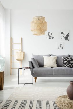 Beyaz Salon iç posterler ve lamba ile gri kanepe yanındaki siyah tablo. Gerçek fotoğraf