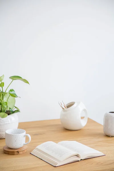 Boek Cup Plant Houten Tafel Tegen Witte Muur Eenvoudige Woonkamer — Stockfoto