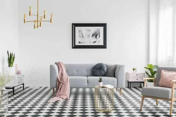 粉红色的毯子和枕头在灰色的沙发在白色客厅内部与海报和扶手椅 真实照片 — 图库照片