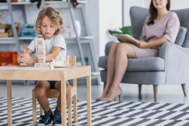 Bir aile destek merkezindeki bir terapist ile tedavi edici bir toplantı sırasında tahta bloklarla oynama Asperger sendromu olan bir çocuk.