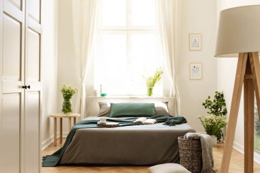 Bitkiler ve yatak üzerinde pencere parlak yatak odası iç lamba ve beyaz kapı. Gerçek fotoğraf