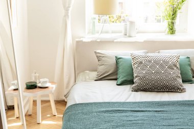 Yastık ve yatak yatak odası iç beyaz üzerine yeşil yaprak ayna için ileri masa. Gerçek fotoğraf