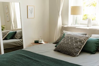 Desenli ve yeşil yastık yatak basit yatak odası iç poster ve ayna ile. Gerçek fotoğraf