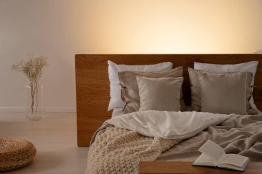 Yastık ve yatak yatak başı çiçek ve kitap ile karanlık yatak odası iç sayfalarda. Gerçek fotoğraf