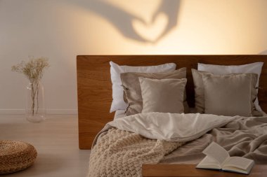 Kalp yastık ve battaniye ile rahat bir yataklı bir yatak odası iç gölge şeklinde. Gerçek fotoğraf