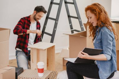 Kızıl saçlı kadın kocasıyla bir düz döşeme sırasında fotoğraf albümü arıyor