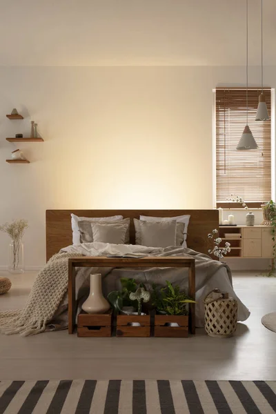 一张双人床与枕头和床头板 桌子和木箱在一个自然的卧室内部的前视图 真正的照片 将图形放置 — 图库照片