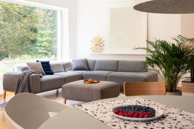 Masaya aydınlık oturma odası iç pencere ve köşe Lounge yastık ile gerçek fotoğraf bulanık ön planda yer meyve ile plaka