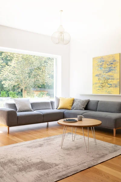 Saç tokası sehpa ile plaka üzerinde yaban mersini ve İskandinav tarzı oturma odası iç pencere, halı üzerinde çay kupa duran gerçek fotoğraf kanepe gri ve soyut resim