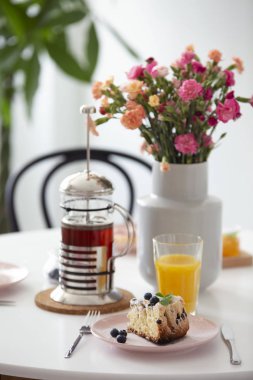 Çiçekler ve tabloda çay ve tatlı bir restoran iç ile portakal suyu. Gerçek fotoğraf