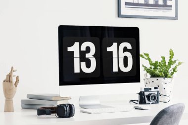 Bilgisayar ekranında gösterilen zaman, kulaklık, kamera, kitaplar, ahşap el bir parlak ofis iç bir masa üzerinde bir bitki