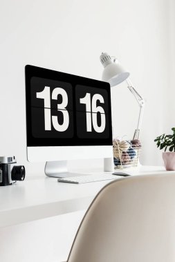 Bir lamba, kamera ve fabrikasında bir ofis iç üzerinde beyaz masa saati gösteren bir ekran Close-up. Gerçek fotoğraf