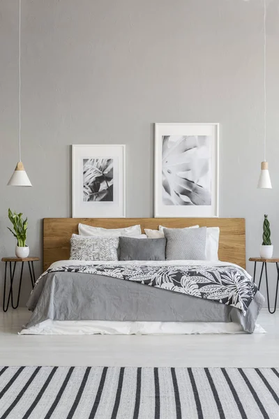 カーペット グレー寝室のインテリアで柄の毛布でベッドの木製のヘッドボードの上にポスター 実際の写真 — ストック写真