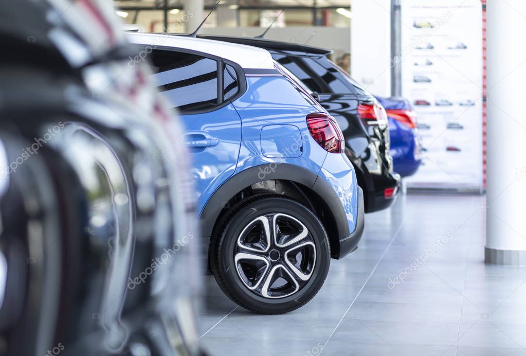 Row of shiny cars for sale parked in a showroom interior
