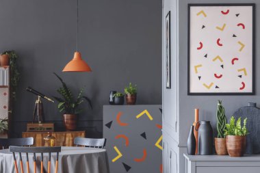 Poster tablosunun yukarısındaki turuncu lambalı gri yemek odası iç geometrik şekiller