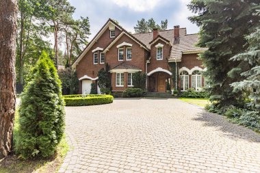 Etkileyici bir kırmızı tuğla önünde büyük Arnavut kaldırımlı driveway İngilizce konak eski ağaçları ile çevrili Tasarla
