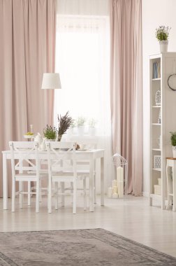 Beyaz sandalye masasında görmek bitkiler pastel pembe yemek odası iç halı ve perdeleri ile. Gerçek fotoğraf