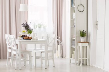 Beyaz sandalyeler yemek masasında görmek bitkiler pembe perdeler ve pencere ile modern düz iç. Gerçek fotoğraf