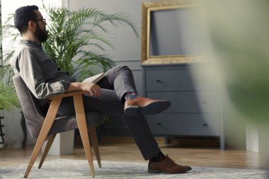 Üretim tesisi ile gri vintage iç ahşap koltukta oturan hipster düşük açılı