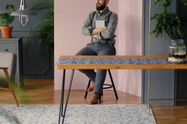 Modern iç masada otururken bir kitap tutan sakallı hippi