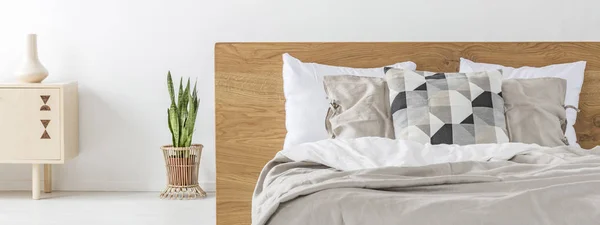 新鮮な植物の白い寝室インテリアに木製のヘッドボード立ってダブルベッドの本物の写真 — ストック写真