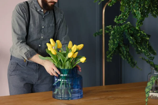 Muž Zahradnické Vášní Uvedení Žluté Tulipány Modrou Vázu Dřevěný Stůl — Stock fotografie