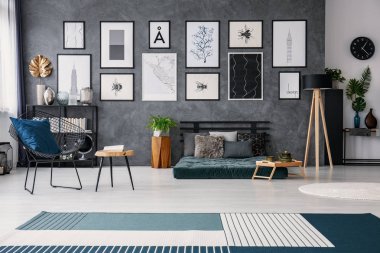 Açık alan iç posterler yukarıda yeşil yatak ve bitki ile tablosunun yanındaki koltuk. Gerçek fotoğraf