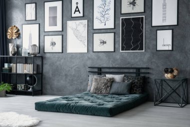 Tablo yanındaki gri yatak odası iç posterler ile yastıkları ile yeşil yatak. Gerçek fotoğraf