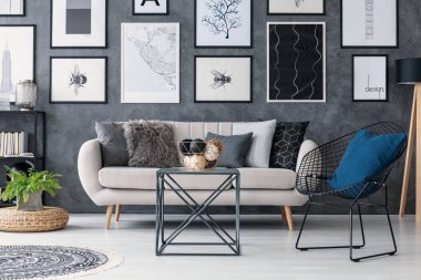 Üzerinde kabarık kanepe gri oturma odası iç masa, koltuk ve posterler için sonraki bitki. Gerçek fotoğraf