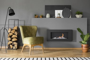 Yeşil koltuk ve odun gri oturma odası iç lamba ile şöminenin yanında. Gerçek fotoğraf