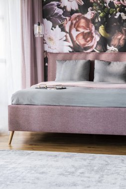 Otel yatak odası iç duvarda yazdırma çiçekli pembe yatak üzerine gri yaprak. Gerçek fotoğraf