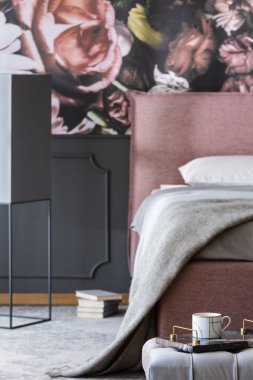 Gri bir battaniye pembe desenli yatak odası iç karanlık duvar kağıdı ile yatakta var. Bir fincan köşesinde mermer tepsi üzerinde odaklanma ile gerçek fotoğraf