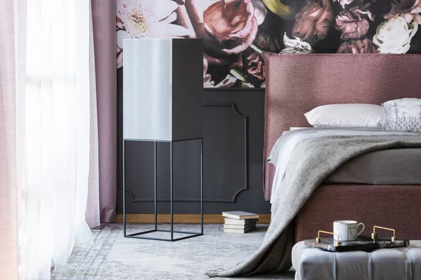 Gri battaniye ve yastıklar çiçek duvar kağıdı ile karanlık yatak odası iç pembe yatakta. Gerçek fotoğraf