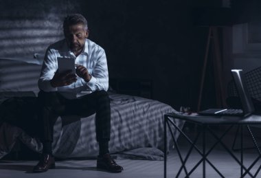 Evde tablet kullanarak bir işkolik. Uykusuzluk sorunu olan işadamı