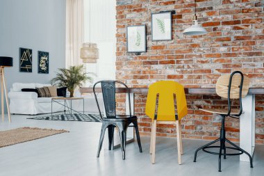 Kırmızı tuğla duvara posterler açık alan iç beyaz kanepe ile ile yemek masası sandalyeler. Gerçek fotoğraf