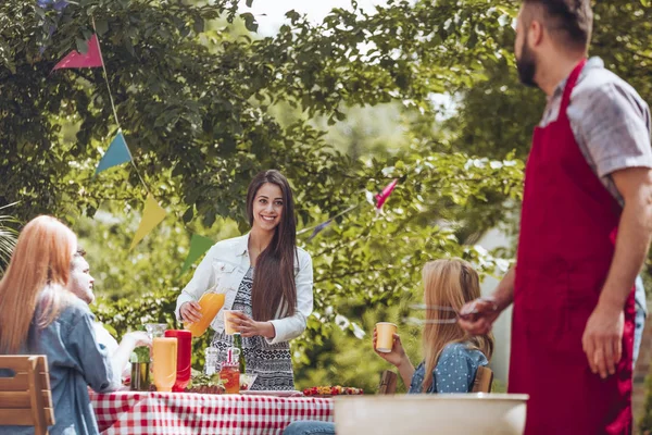 Ung Flicka Häller Apelsinjuice Kopp Och Man Vinröd Förkläde Grillning — Stockfoto