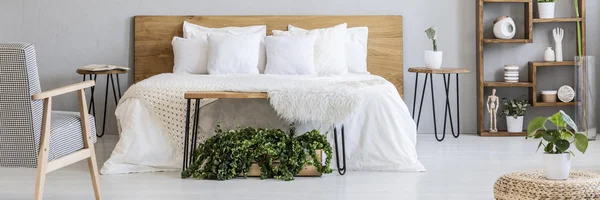 キングサイズのベッドの白いシーツとヘアピン ベッドサイド テーブルと灰色の寝室のインテリアに立って多くの枕の実際の写真 — ストック写真
