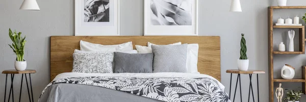 ダブルベッド つのポスターや新鮮な植物と寝室のインテリアの本物の写真で木製のヘッドボード立っての花の寝具 — ストック写真