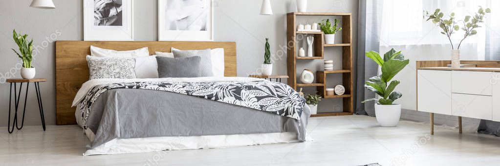 Scandinavian style, wooden furniture in a stylish, monochromatic bedroom interior with plants, gray walls and industrial elements