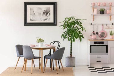Mutfak iç poster ve pembe aksesuarlar ile bitkilerde yanında yemek masası sandalyeler gri. Gerçek fotoğraf