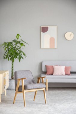 Ahşap tekli kanepe yastık ile yukarıda posteri ile pembe ve gri oturma odası iç. Gerçek fotoğraf