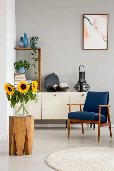 向日葵在木凳附近蓝色扶手椅在灰色客厅内部与海报 真实照片 — 图库照片
