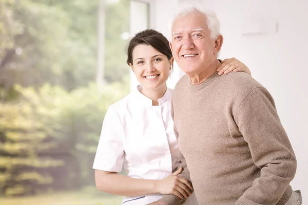 Friendly Smiling Caregiver Hugging Happy Elderly Man Hospital — Stock Photo, Image