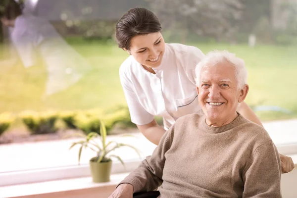 Miła Pielęgniarka Wspieranie Niepełnosprawnych Uśmiechający Się Starszy Człowiek Domu Opieki — Zdjęcie stockowe